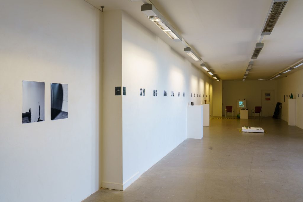 Exhibition view with prints on the wall, disappearing in distance